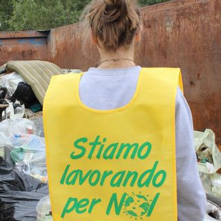 Un volontario di Puliamo il mondo di spalle, con pettorina gialla