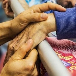 mani di un anziano che stringono altre mani