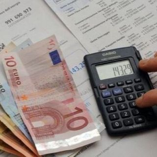 soldi in contanti e una mano che usa una calcolatrice