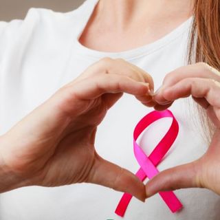 donna fa con la mani il simbolo della lotta al cancro al seno