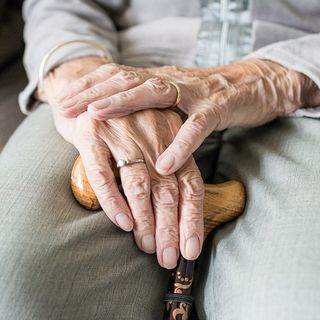 Mani di persona anziana che reggono un bastone