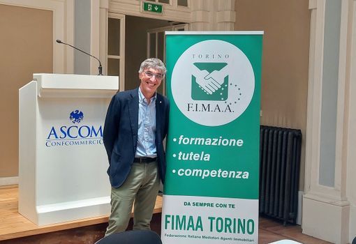 Uomo sorridente in posa davanti ad alcuni cartelloni