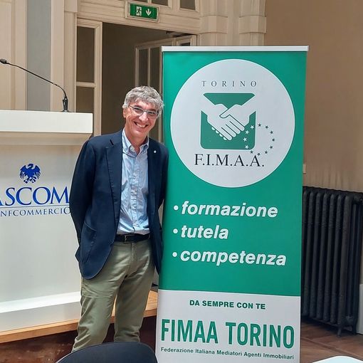 Uomo sorridente in posa davanti ad alcuni cartelloni