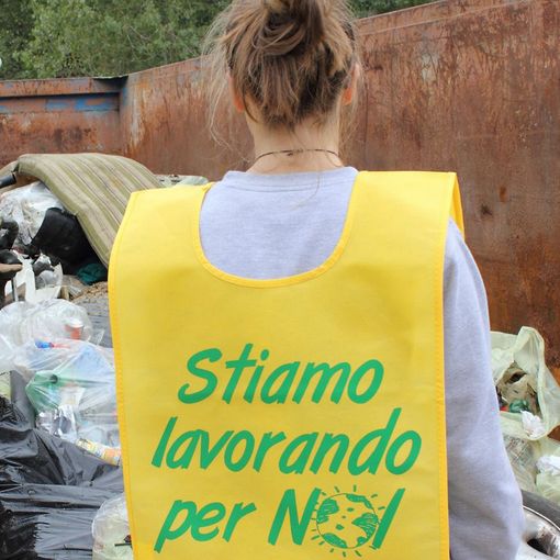 Un volontario di Puliamo il mondo di spalle, con pettorina gialla