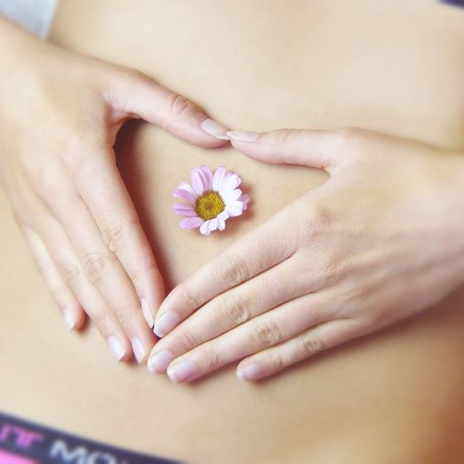Donna con le mani sulla pancia e una margherita sull'ombelico