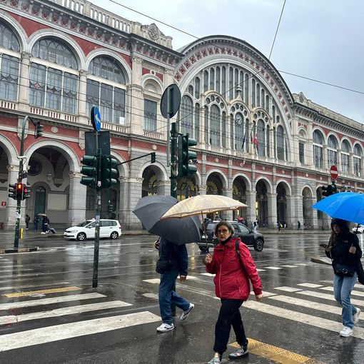 persone sotto la pioggia davanti a Porta Nuova
