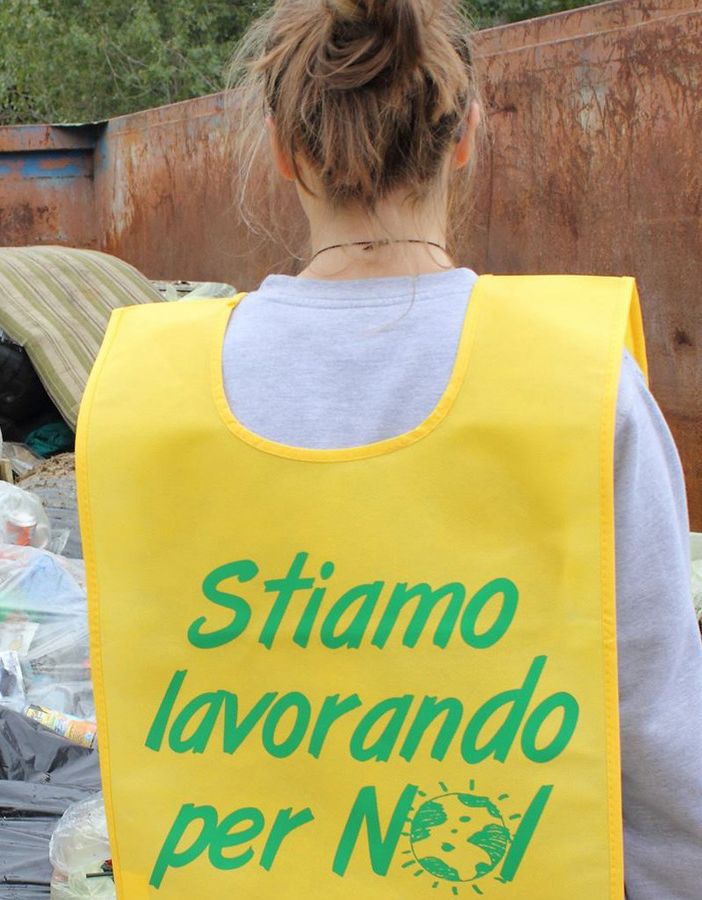 Un volontario di Puliamo il mondo di spalle, con pettorina gialla