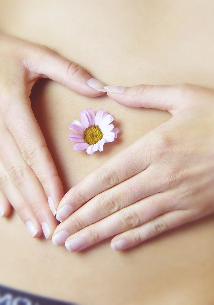 Donna con le mani sulla pancia e una margherita sull'ombelico