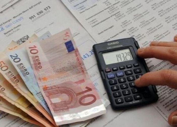 soldi in contanti e una mano che usa una calcolatrice