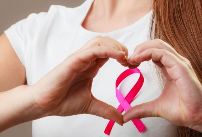 donna fa con la mani il simbolo della lotta al cancro al seno