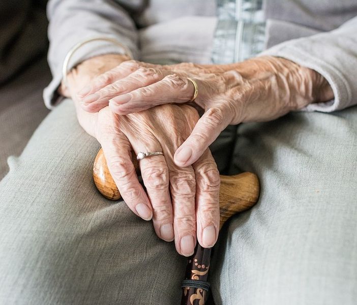 Mani di persona anziana che reggono un bastone