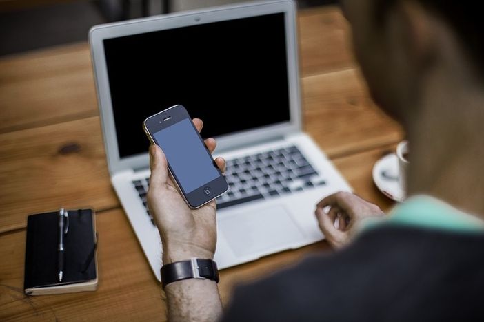 Uomo al pc con un cellulare in mano