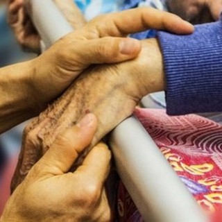 mani di un anziano che stringono altre mani