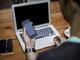 Persona con in mano un cellulare e un pc